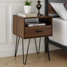 a bedside table with two drawers on one side and a plant on the other end