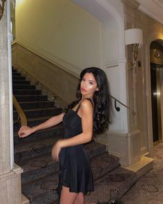 a beautiful young woman standing next to a stair case