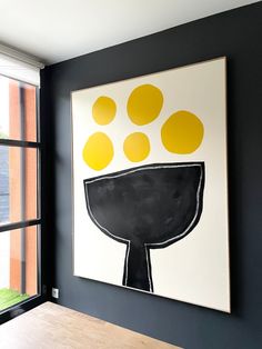 a black and white painting hanging on the wall next to a window with yellow circles