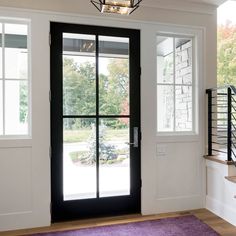 the front door is open and there are stairs leading up to the room with glass doors