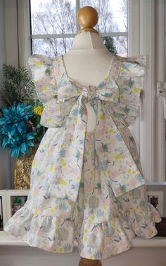 a dress on a mannequin in front of a window with flowers and leaves