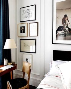 a bedroom with pictures on the wall and a desk in front of it next to a bed