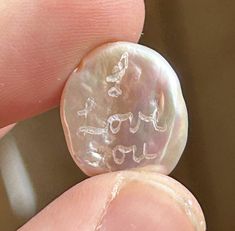 a close up of a person's finger holding a small button with writing on it