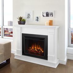 a white fireplace with flames in it and pictures on the wall