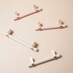 three white and gold handles on a pink surface, one with two bars attached to it