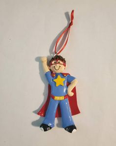 a ceramic ornament shaped like a superman with a red cape and yellow star on his chest