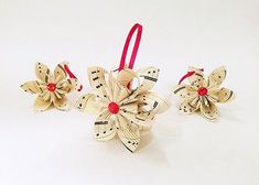 three ornaments made out of sheet music and red ribbon on white surface with copy space for text