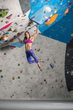 a woman climbing up the side of a rock wall with her arms in the air