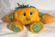 a yellow stuffed animal sitting on top of a white bed sheet covered in green and gold decorations