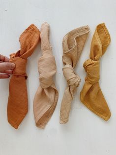 three different types of ties laid out on a white surface with one being held up to the camera