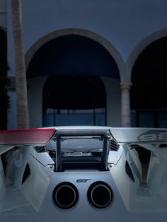 the rear end of a white car with speakers on it's roof and front bumper