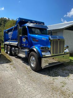 a blue dump truck parked in front of a building