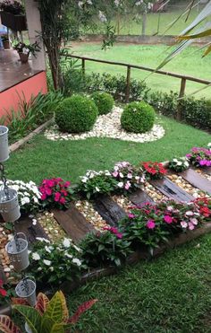 a garden with lots of flowers and rocks in the grass next to a wooden fence