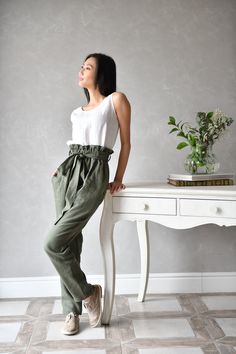 "SIZING AND FIT The pants are true to size with an elastic waistband and tie - we recommend choosing the size you usually wear. Before placing an order check our size chart below. The model in the picture is wearing size XS in color olive green. SIZE XS Bust: around 33.5\" / 85cm Waist: around 26\" / 66cm Hips: around 36\" / 91 cm SIZE S Bust: around 35.5\" / 90 cm Waist: around 28\"/ 71 cm Hips: around 38\"/ 97 cm SIZE M Bust: around 37.5\" / 95 cm Waist: around 30\"/ 76 cm Hips: around 40\"/ 1 Relaxed Fit Tapered Leg Bottoms With Tie Waist, Cotton Pants With Tie Waist And Tapered Leg, Cotton Tapered Leg Pants With Tie Waist, Linen Paperbag Waist Pants For Summer, Casual Tie Waist Paperbag Bottoms, Summer Linen Pants With Paperbag Waist, Relaxed Fit Bottoms With Paperbag Waist And Belt Loops, Summer Linen Paperbag Waist Pants, Cotton Paperbag Waist Pants With Tie