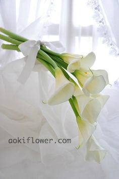 a bouquet of white flowers sitting on top of a bed in front of a window