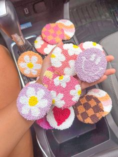 a person is holding some crocheted flowers in their hand while sitting in the car