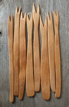 six wooden spoons lined up on top of each other, with long tooth tips sticking out of them