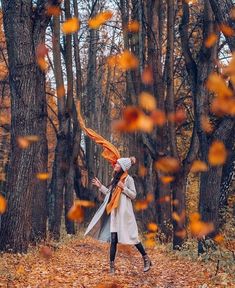 a woman is walking through the woods with an orange scarf