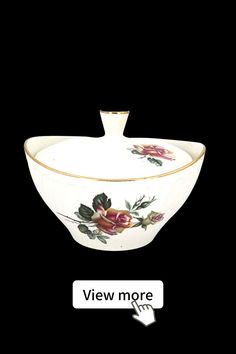 a white bowl with flowers painted on it and the words view more below in gold lettering