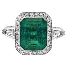 A stunning engagement ring, featuring a bezel-set 4.58 carats emerald cut green emerald. Surrounded by round brilliant cut diamonds in a halo design and features tapered baguette diamonds on both sides. Accent diamonds weigh 0.64 carat total. Elegantly finished with milgrain edges. Made with 18K white gold. Size 6.5 US, resizable upon request. Roman Malakov is a custom house, specializing in creating anything you can imagine. If you would like to receive a special quote on a custom piece, please Timeless Engagement Ring, Halo Design, Modern Engagement Rings, Stunning Engagement Ring, Dress Rings, Halo Diamond Engagement Ring, Pretty Rings, Rings Jewelry, Green Emerald