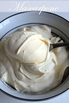 a bowl filled with whipped cream on top of a white tablecloth next to a spoon