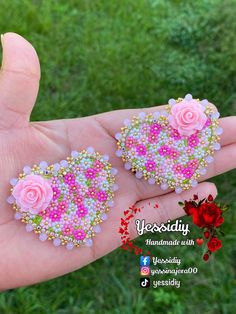 two pink roses are on the palm of someone's hand with beaded earrings