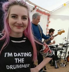 a woman with pink hair standing in front of a band