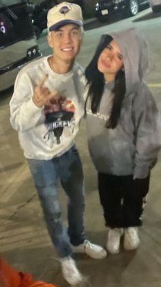 a man and woman standing next to each other in front of a parking lot at night