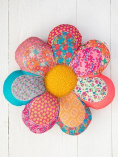 a colorful flower shaped object hanging on the side of a white wooden wall with flowers painted on it