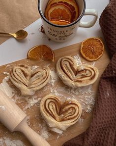 some oranges and cinnamon rolls on a cutting board next to a cup of coffee