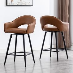 two brown leather bar stools sitting next to each other in front of a window