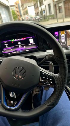 the interior of a car with steering wheel controls and dashboard screen showing various electronic devices