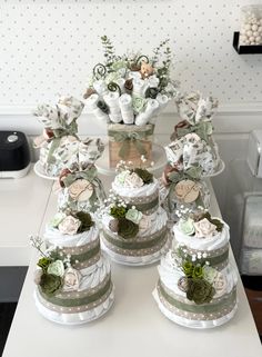 a table topped with lots of cakes covered in white frosting and green flowers on top of each cake