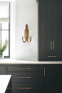 a kitchen with black cabinets and gold handles