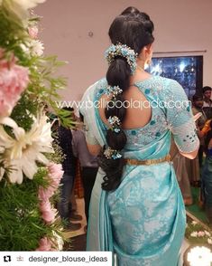 a woman in a blue sari standing next to flowers and people looking at her