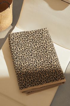 a leopard print notebook sitting on top of a white table next to a wicker basket