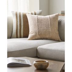 a close up of a couch with pillows on it and a coffee table in the foreground