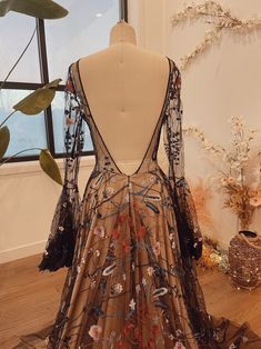 the back of a dress on display in front of a window with flowers and leaves