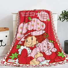 the strawberry shortcake blanket is on display next to a potted plant and stuffed animal