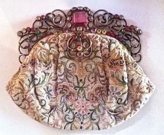 "This hard to find Hobe and Josef handbag with beaded and embroidered body has the breathtaking brilliant stones set in gold tone wirework typical of Hobe quality. The phenomenal frame is encrusted with one large pink square stone, then smaller pink, lavender, green, yellow and green faceted imported stones that truly sparkle in the light. A matching hinged clasp completes the piece. it is marked inside \"Hand beaded in USA by Josef\".  The bag itself is wonderful on its own. Hand beaded with ti Vintage Handwork Evening Bag For Party, Vintage Evening Bag With Handwork For Formal Occasions, Vintage Handwork Evening Bag For Wedding, Vintage Wedding Evening Bag With Handwork, Vintage Wedding Bags With Gold Embroidery, Vintage Gold Handcrafted Bag, Vintage Embroidered Event Bag, Vintage Embroidered Bags For Events, Vintage Gold Bags With Handwork