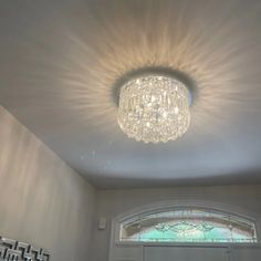 a chandelier hanging from the ceiling in a room with white walls and windows