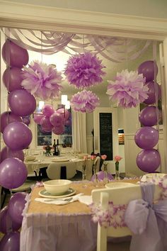 purple balloons are hanging from the ceiling over a dining room table