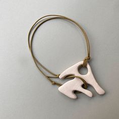 a white and gold necklace with two pieces of wood on the front, one piece is shaped like an elephant's head