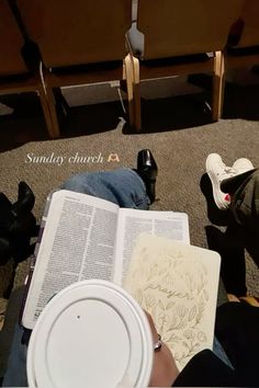 a person sitting on the floor with an open book in front of them and two empty chairs behind them