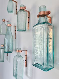 several glass bottles hanging on the wall with copper fittings and brackets attached to them