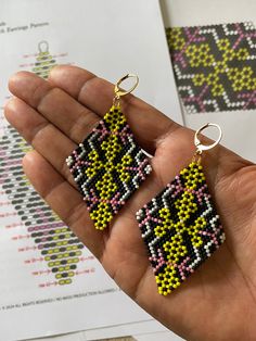 a hand holding two pairs of beaded earrings