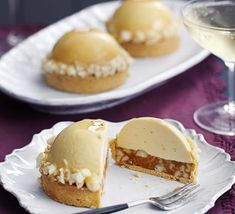 two plates with desserts on them next to a glass of wine