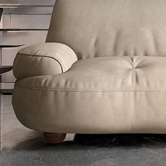 a beige leather couch sitting on top of a hard wood floor next to a table