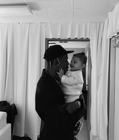 a black and white photo of a man holding a baby in front of a mirror