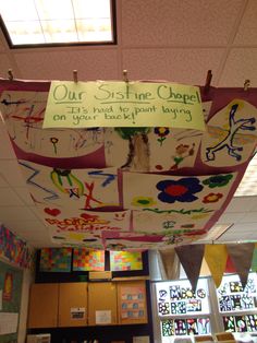 a classroom ceiling decorated with lots of colorful pictures and writing on the paper that says our story is one chapel